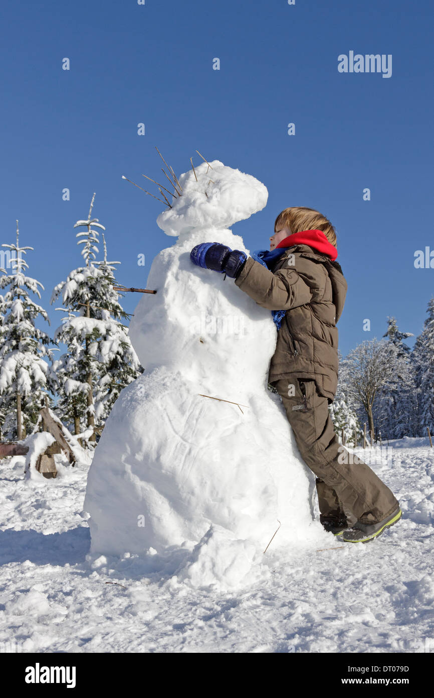 Ragazzo giovane costruire un pupazzo di neve su Kahler Asten vicino a Winterberg, Sauerland, Renania Settentrionale - Westfalia, Germania Foto Stock