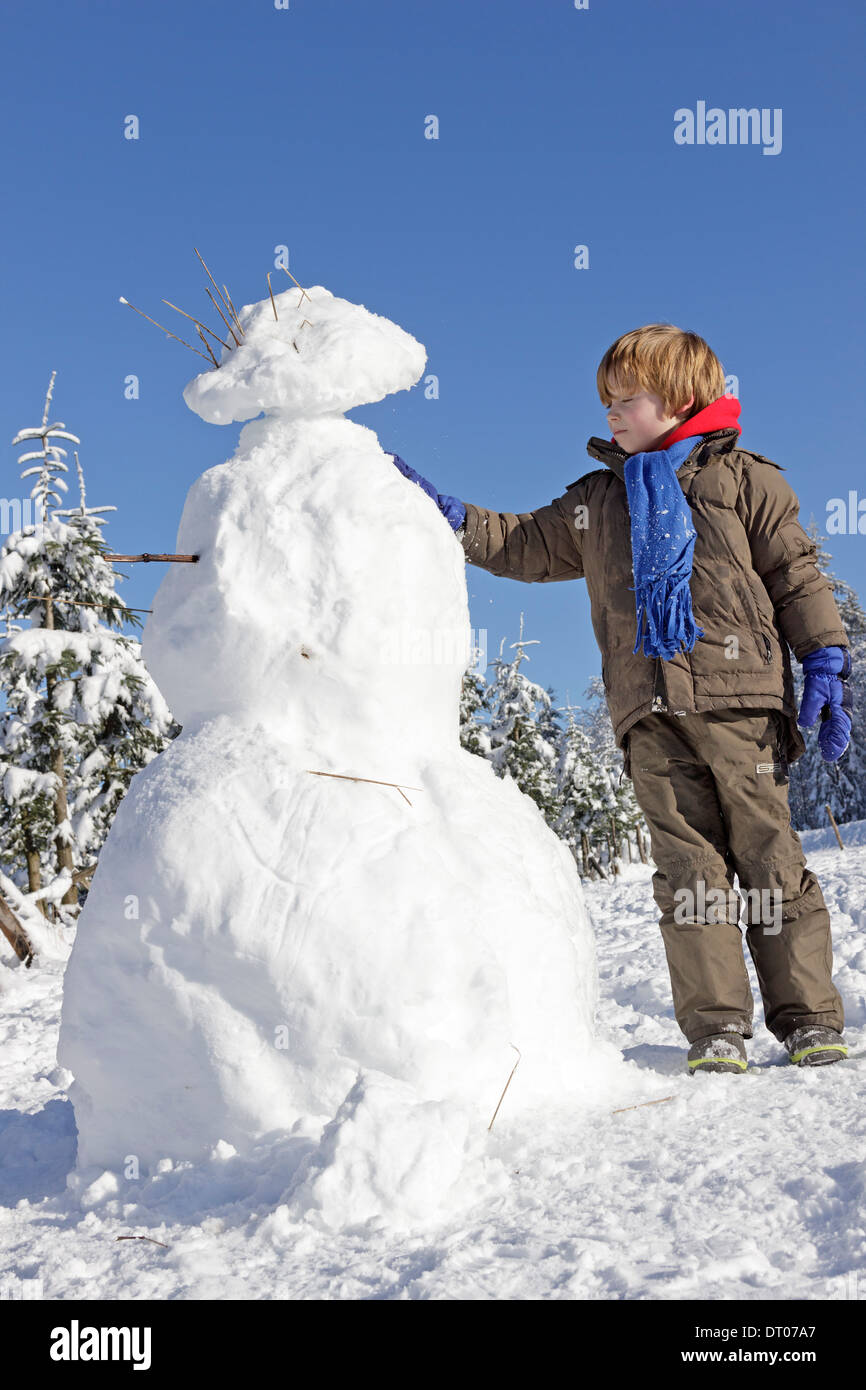 Ragazzo giovane costruire un pupazzo di neve su Kahler Asten vicino a Winterberg, Sauerland, Renania Settentrionale - Westfalia, Germania Foto Stock