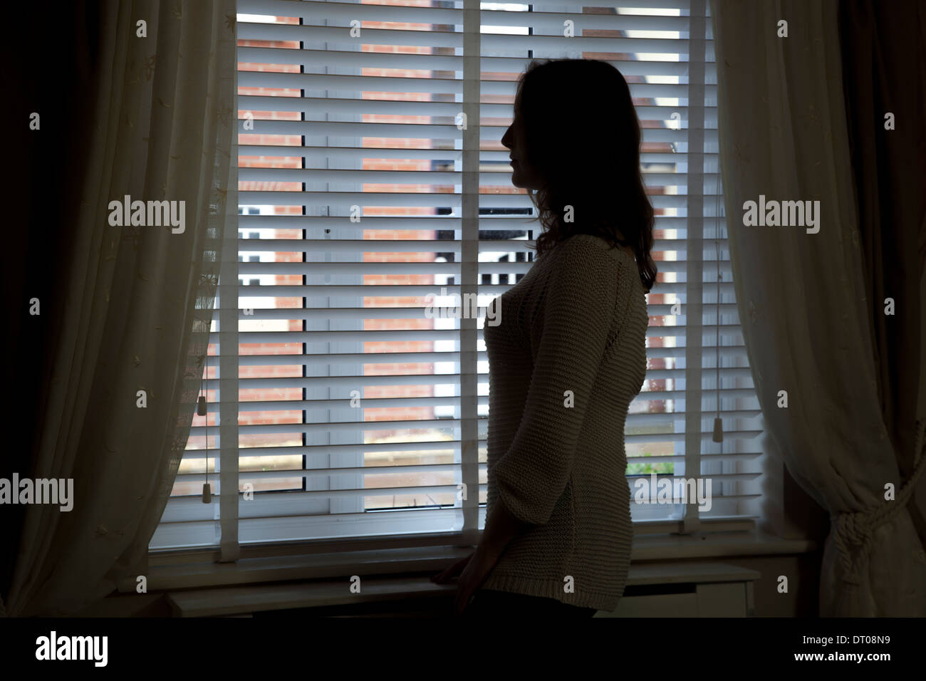 Silhouette di donna in piedi da una finestra. Sulla spalla vista posteriore/laterale. Foto Stock