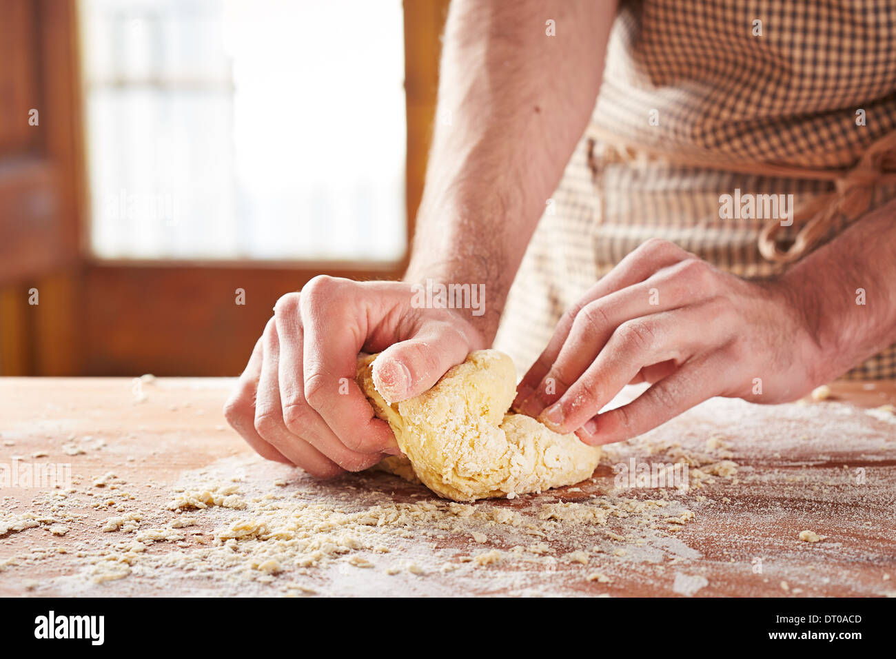 Baker con le mani in mano la cottura la pasta su un tavolo di legno Foto Stock