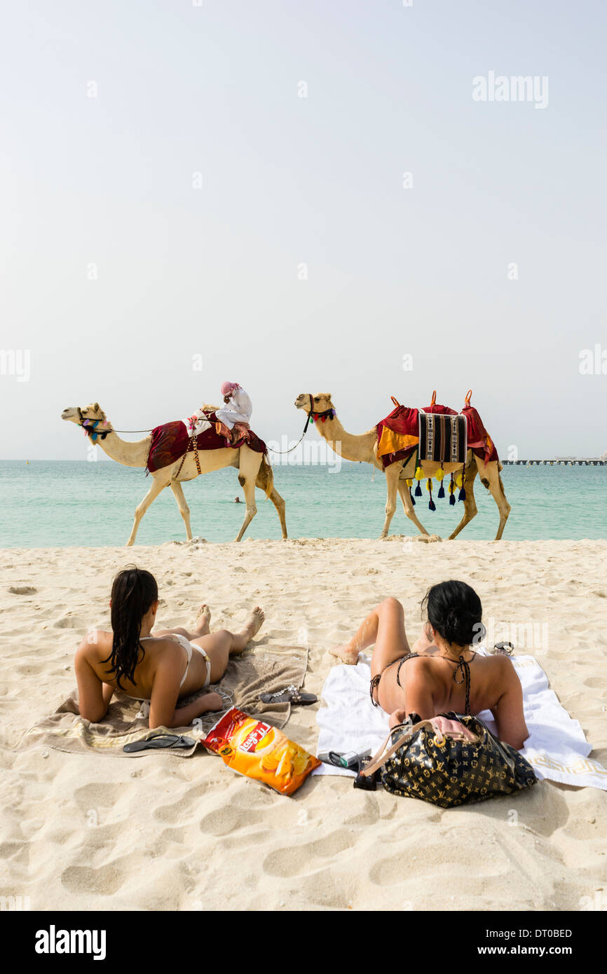 Turista corsa in cammello sulla spiaggia di Marina District di New Dubai negli Emirati Arabi Uniti Foto Stock