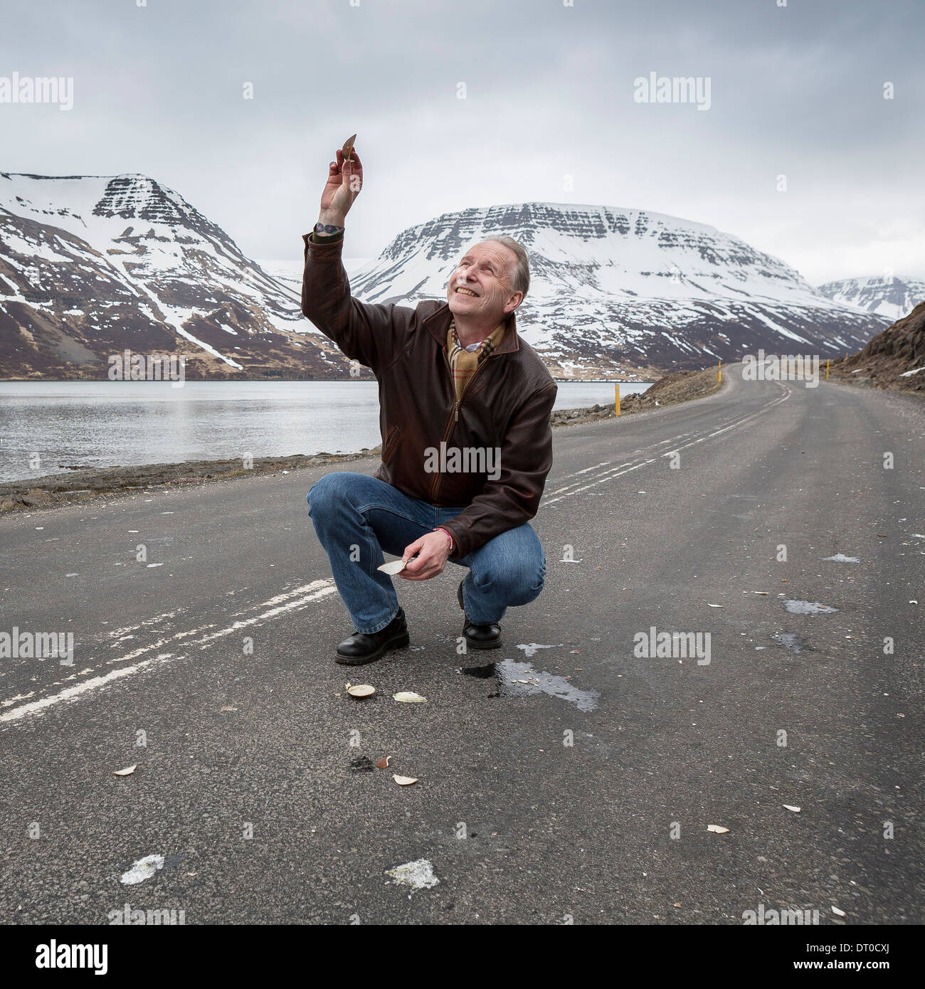 Geophysicist in strada cercando di ottenere l'attenzione degli uccelli che volano sopra, Sugandafjordur, Occidentale, Islanda Foto Stock
