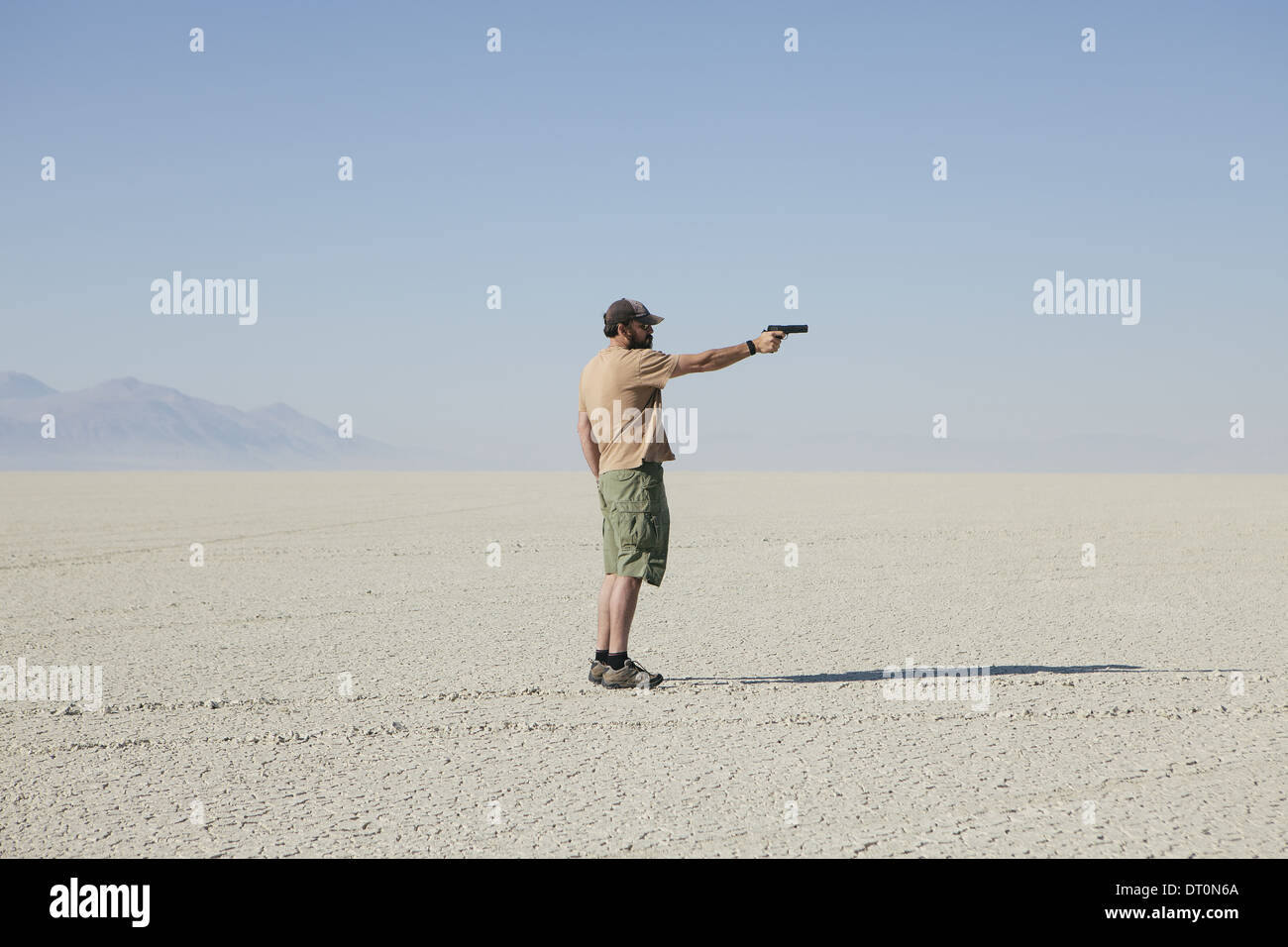 Black Rock Desert Nevada USA uomo mirando a pistola in piedi nel vasto deserto arido Foto Stock