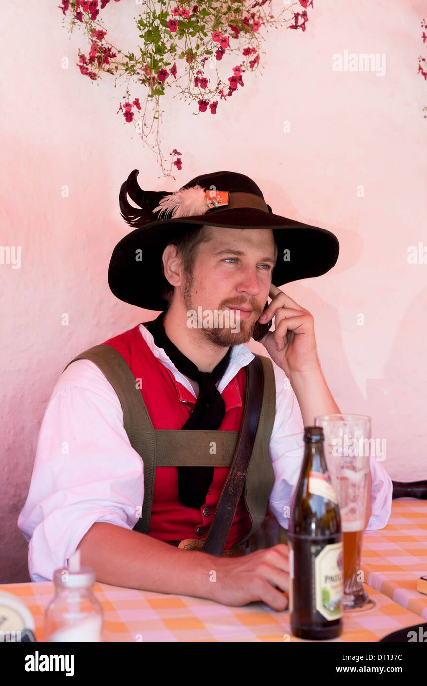 Giovane uomo utilizzando il cellulare al festival della birra nel villaggio di Klais in Baviera, Germania Foto Stock