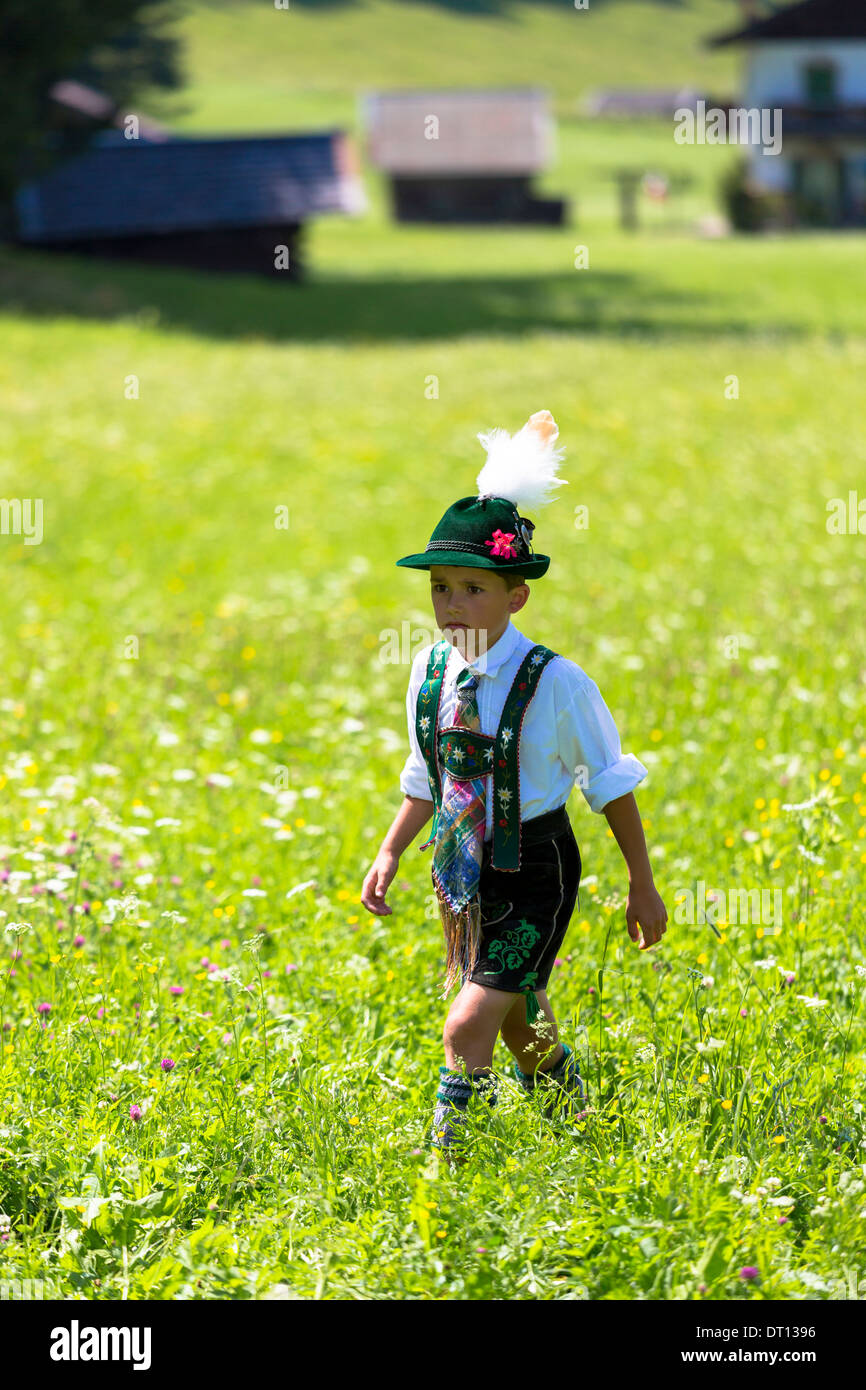 Giovane ragazzo in costume passeggiate attraverso prati di fiori durante la tradizionale festa della birra nel villaggio di Klais in Baviera, Germania Foto Stock