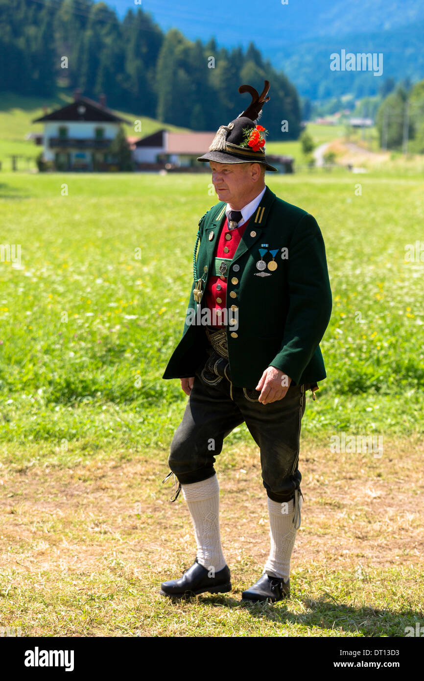 Uomo in costume passeggiate attraverso prati di fiori durante la tradizionale festa della birra nel villaggio di Klais in Baviera, Germania Foto Stock