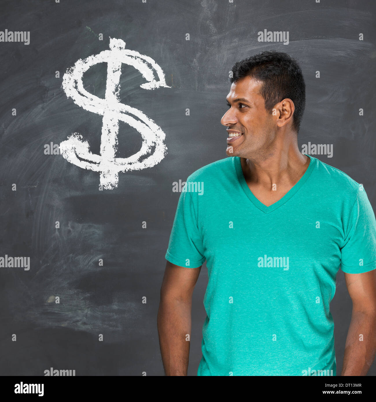 Felice l'uomo indiano in piedi di fronte a dollar sign scritto su una lavagna. Foto Stock