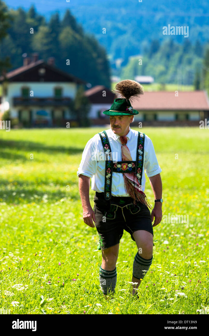 Uomo in costume passeggiate attraverso prati di fiori durante la tradizionale festa della birra nel villaggio di Klais in Baviera, Germania Foto Stock