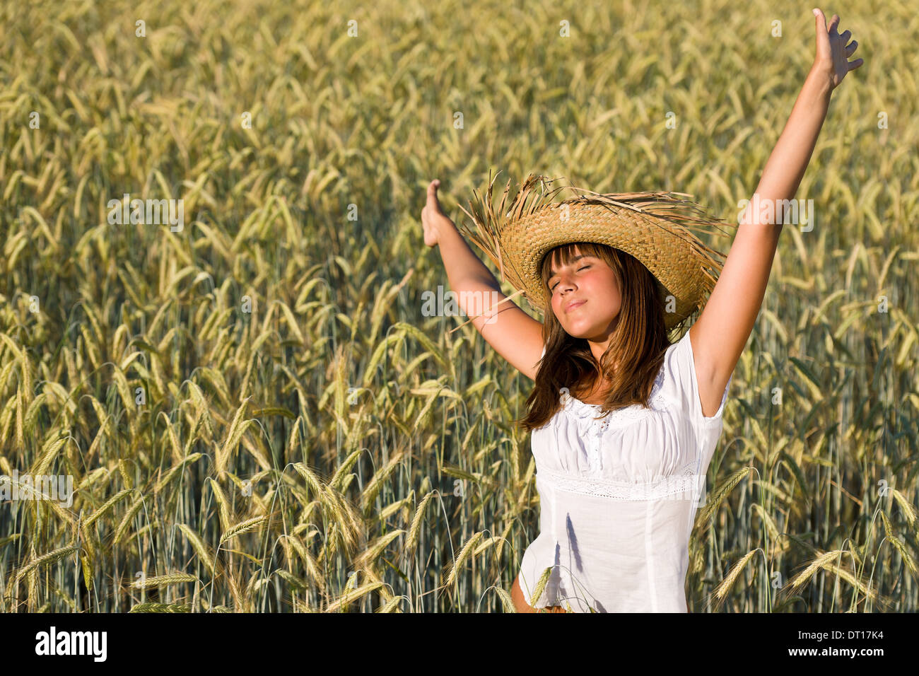 Felice donna con cappello di paglia nel campo di grano Foto Stock