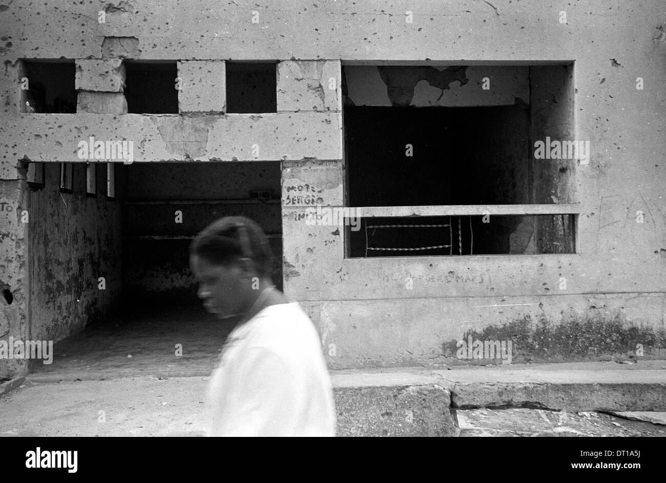 Danni della bomba. Una donna cammina davanti a un edificio rovinato dal SADF durante l'anti ANC milatary azione prima di democrazia in Sud Foto Stock