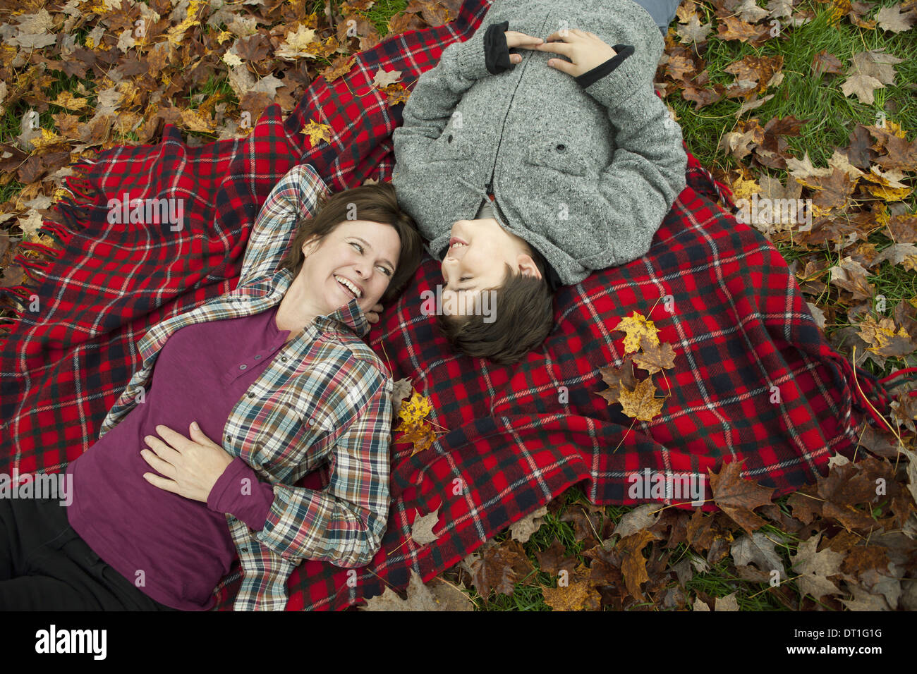 Due persone una donna e un bambino giacente su un tartan rosso Coperta picnic guardando verso l'alto Foto Stock