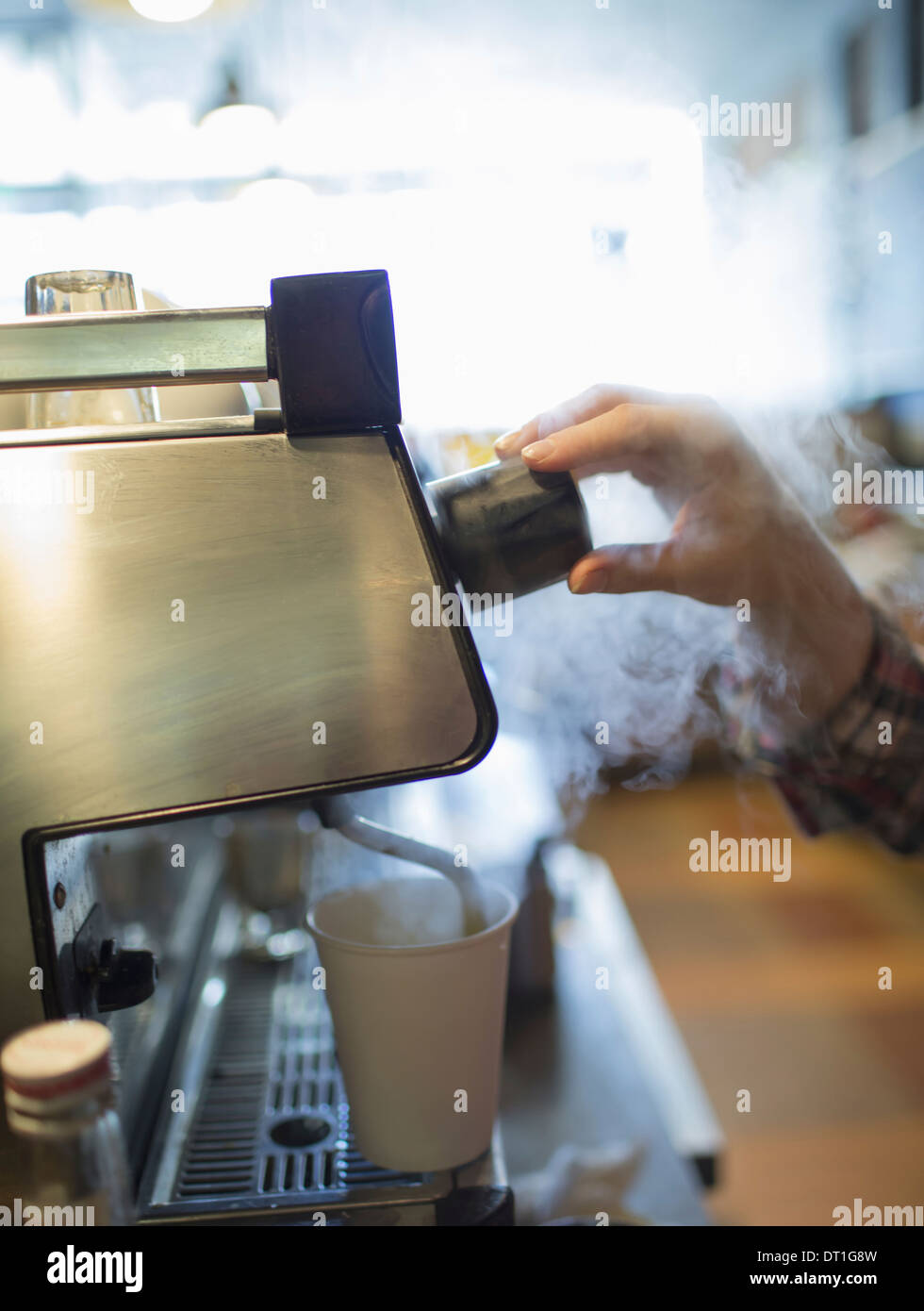 Una persona barista il caffè e la preparazione di schiuma di latte usando un tubo di vapore Coffee shop Foto Stock