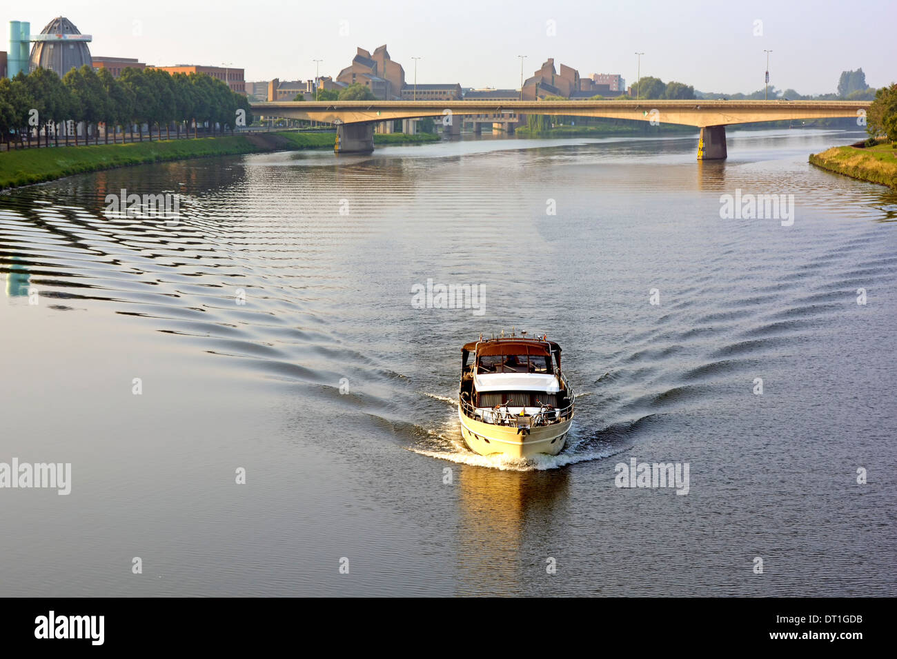 Il motoscafo si svela attraverso l'acqua del fiume ferma il sole della mattina presto sul ponte che attraversa il fiume Mosa Maastricht Limburgo, Paesi Bassi Europa Foto Stock