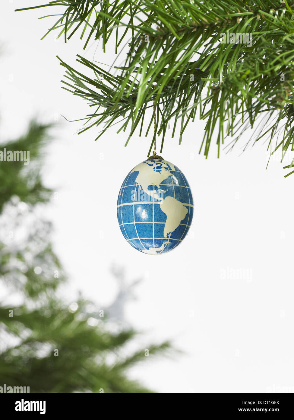 Decorazioni un pino ramo e un blu e bianco ninnolo un globo con continenti delineato su uno sfondo blu Foto Stock