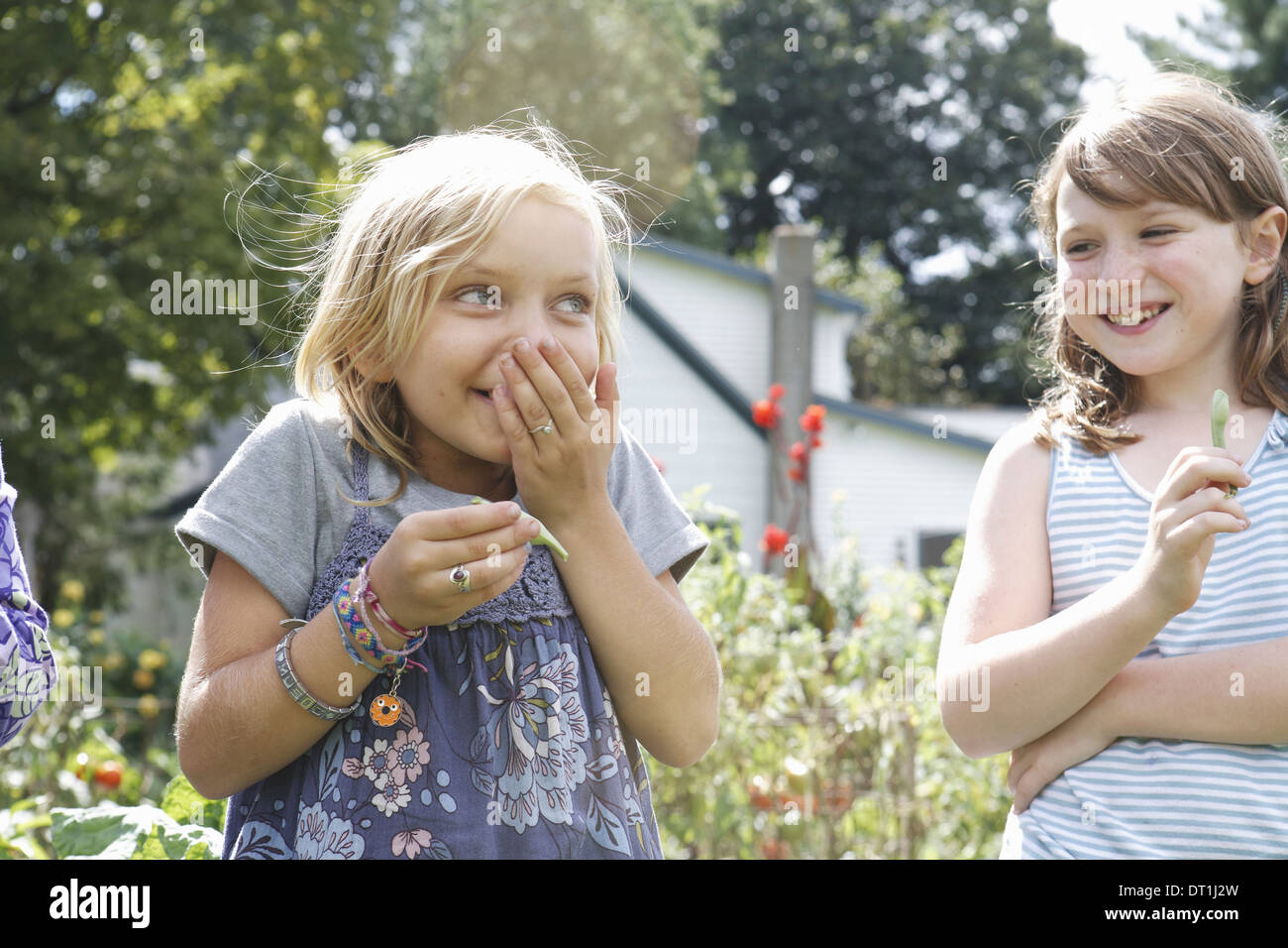 Due bambini in piedi all'aperto in un giardino di ridere Foto Stock