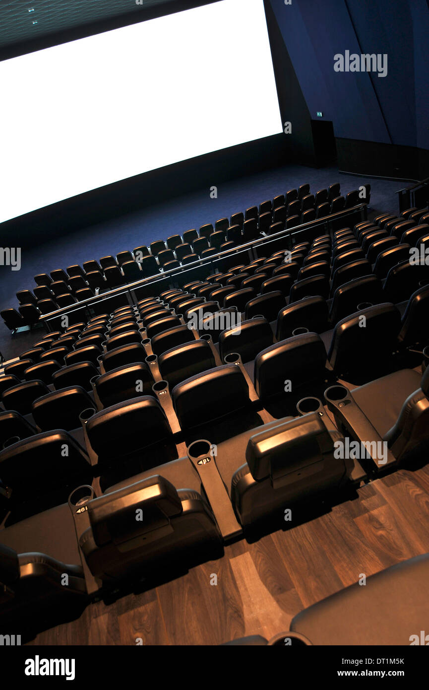 Interno del cinema auditorium visto dalla parte superiore con le file di sedili e bianca cinema schermo nella parte anteriore Foto Stock
