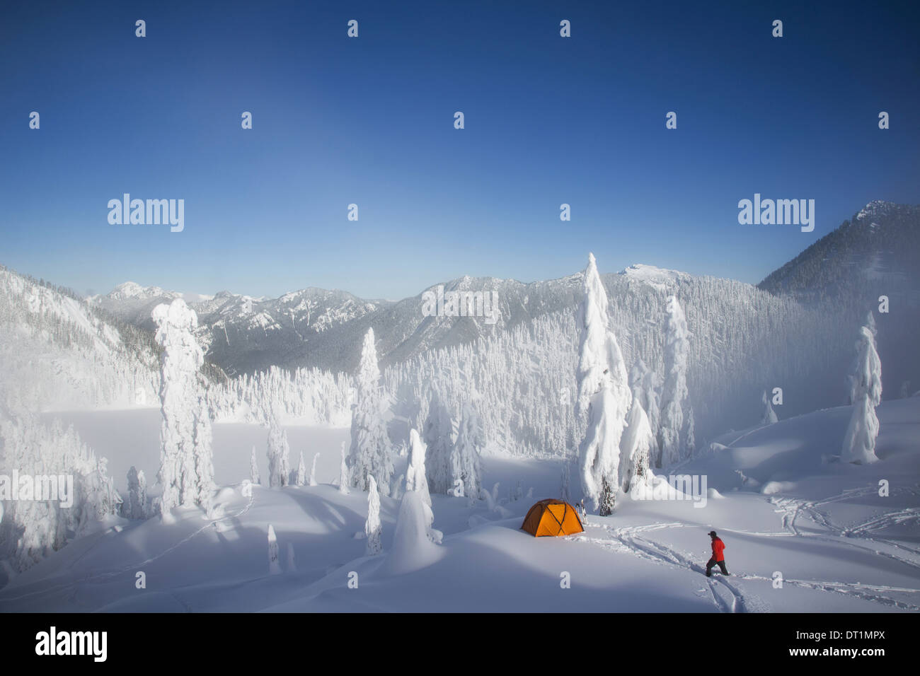 Michael Hanson passeggiate attraverso le profonde in polvere per il suo campeggio nella coperta di neve Cascade Mountains affacciato sul lago di neve Foto Stock