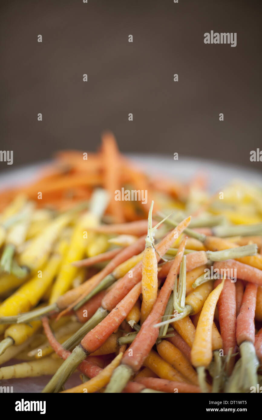 Gli ortaggi biologici in un piatto cucinato giallo arancione e rosa heritage carotine Farm stand produrre Foto Stock