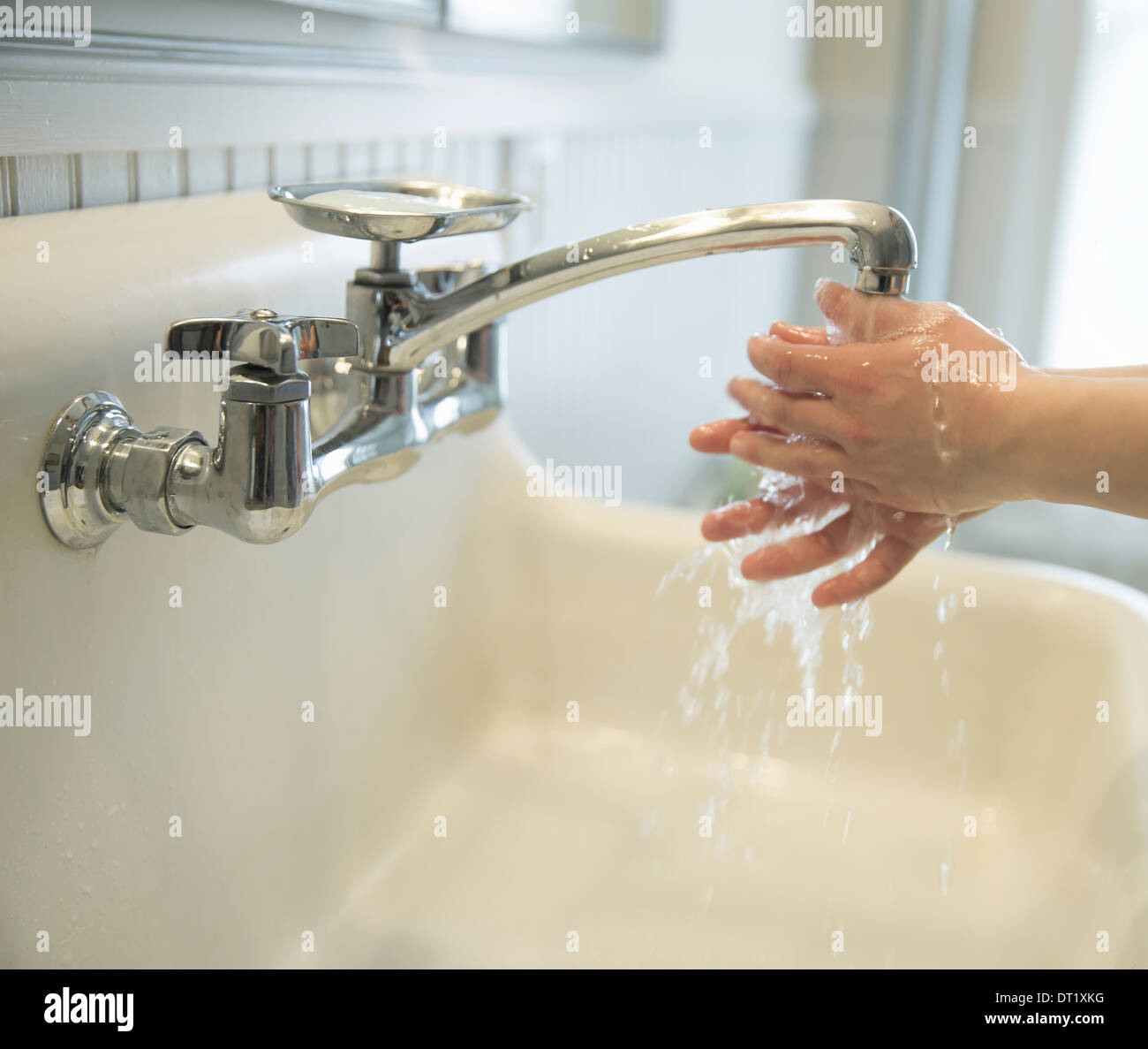Un ragazzo lavarsi le mani sotto il rubinetto da bagno Foto Stock