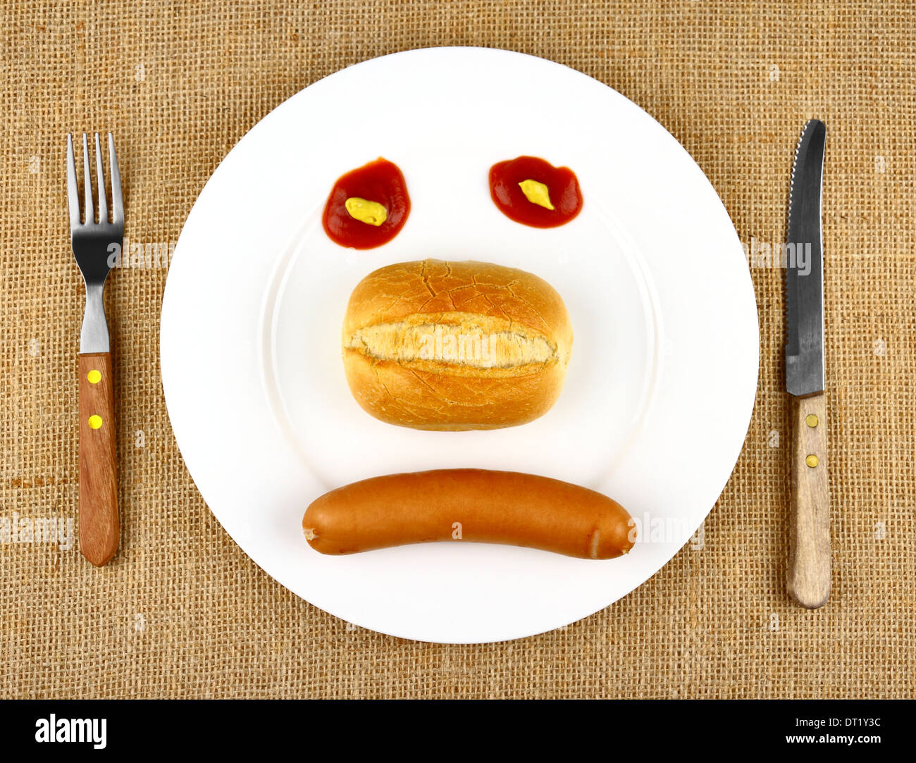 La salsiccia con bun sulla piastra come triste faccia vista superiore Foto Stock