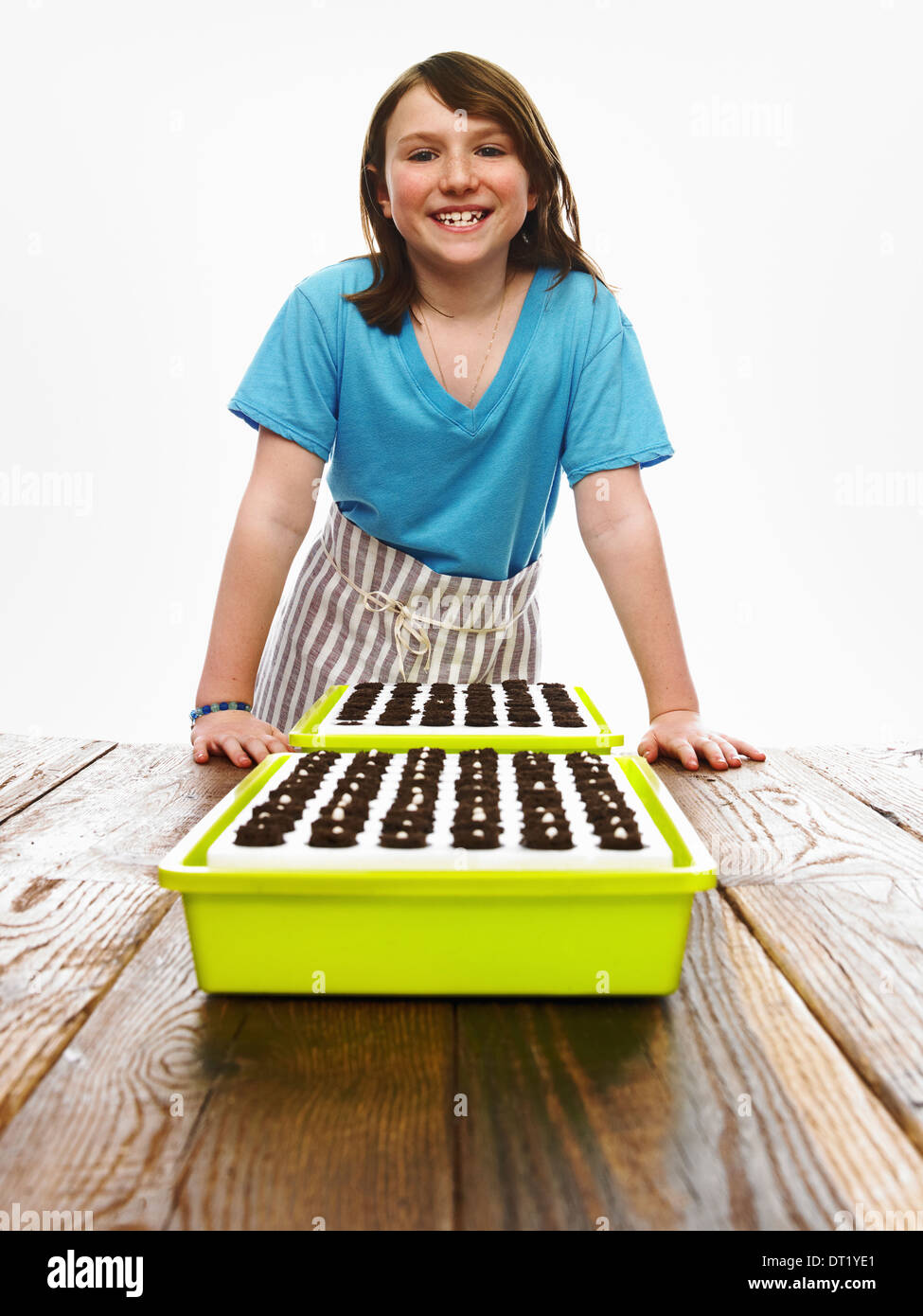Una giovane ragazza appoggiato su un tavolo con due vassoi di appena piantato i semi in appoggio sul buio suolo organico Foto Stock