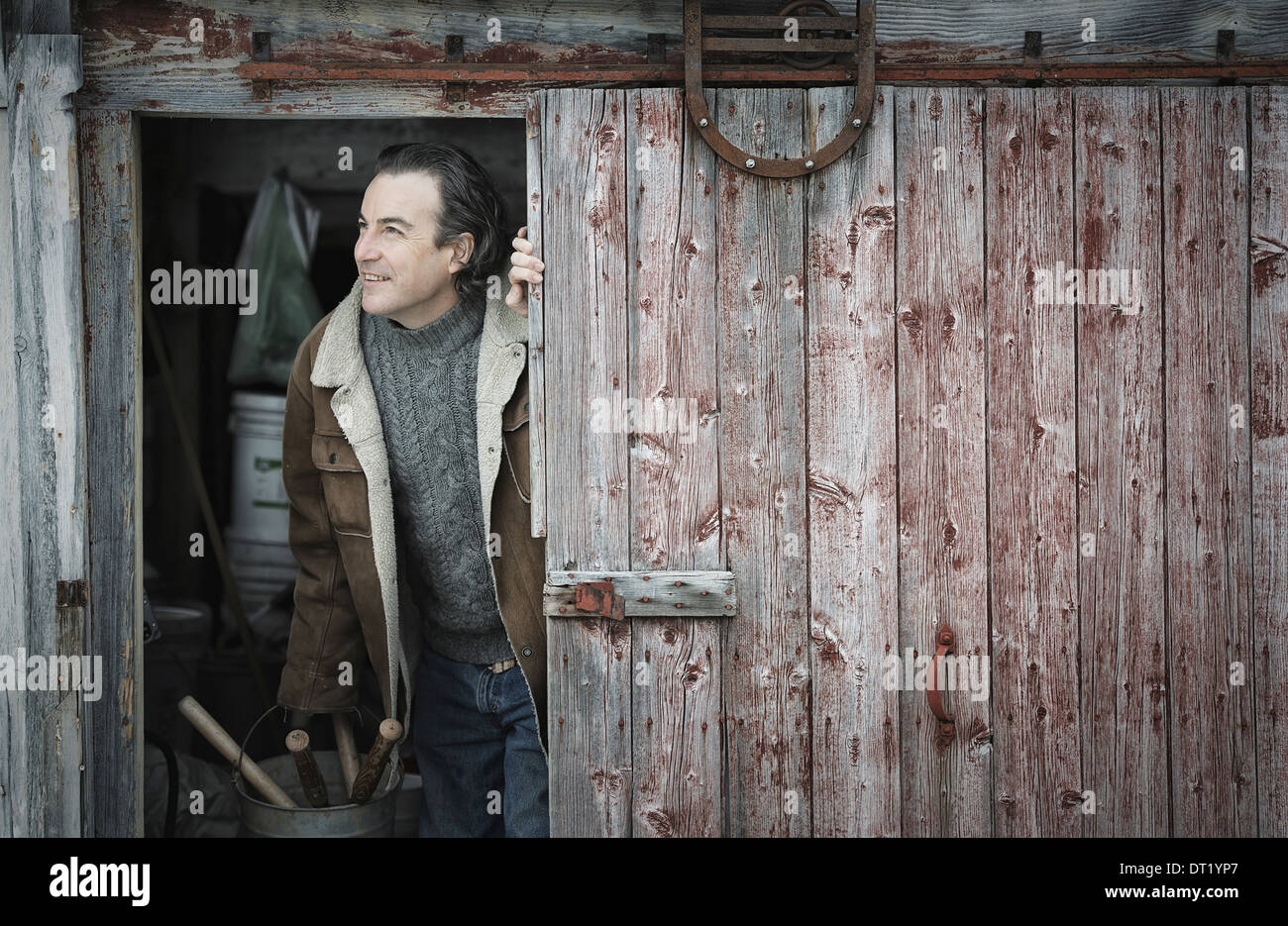 Un agriturismo biologico in Upstate New York in inverno un uomo ad un apri porta del granaio Foto Stock