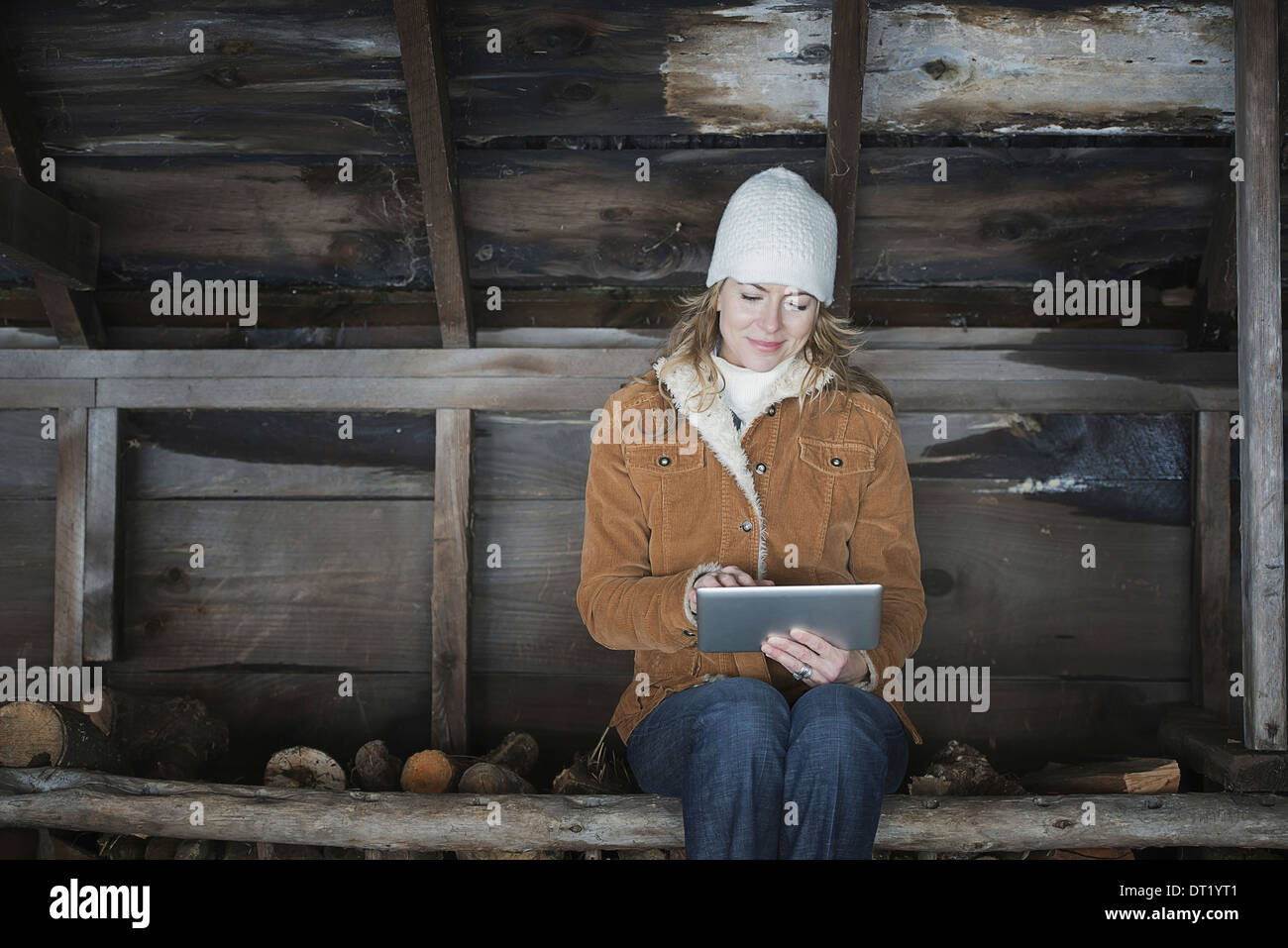 Un agriturismo biologico in Upstate New York in inverno una donna seduta in una dependance utilizzando una tavoletta digitale Foto Stock