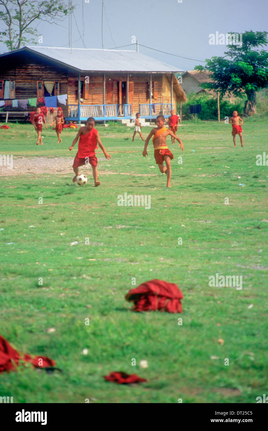 I giovani monaci buddisti che giocano a calcio (calcio) al Lago Inle, Birmania (Myanmar). Le loro vesti giacciono gettati a terra. Foto Stock