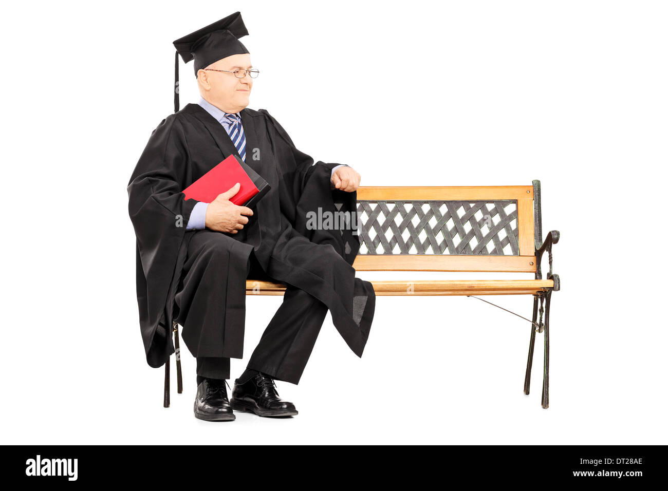 Uomo maturo in abito di graduazione seduto sulla panca di legno e libri di contenimento Foto Stock