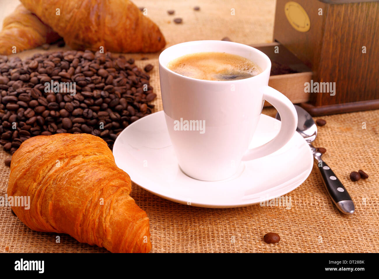 Caffè in tazza bianca, una smerigliatrice e croissant, close up Foto Stock