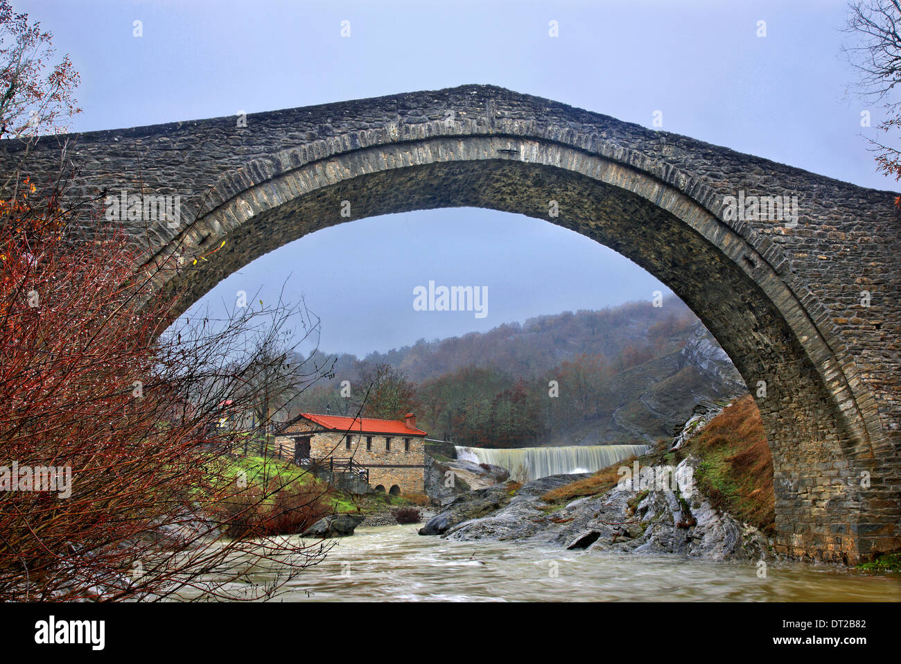 Antica pietra ponte arcuato, mulino e la cascata nel villaggio Chrysavgi, Voio montagna, Kozani, Macedonia, Grecia Foto Stock