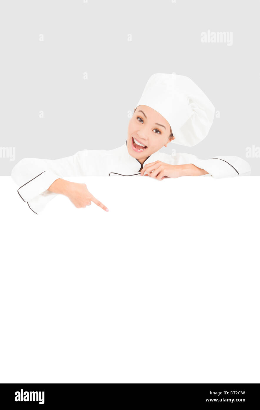 Sorridente donna giovane chef con puntamento blank board Foto Stock