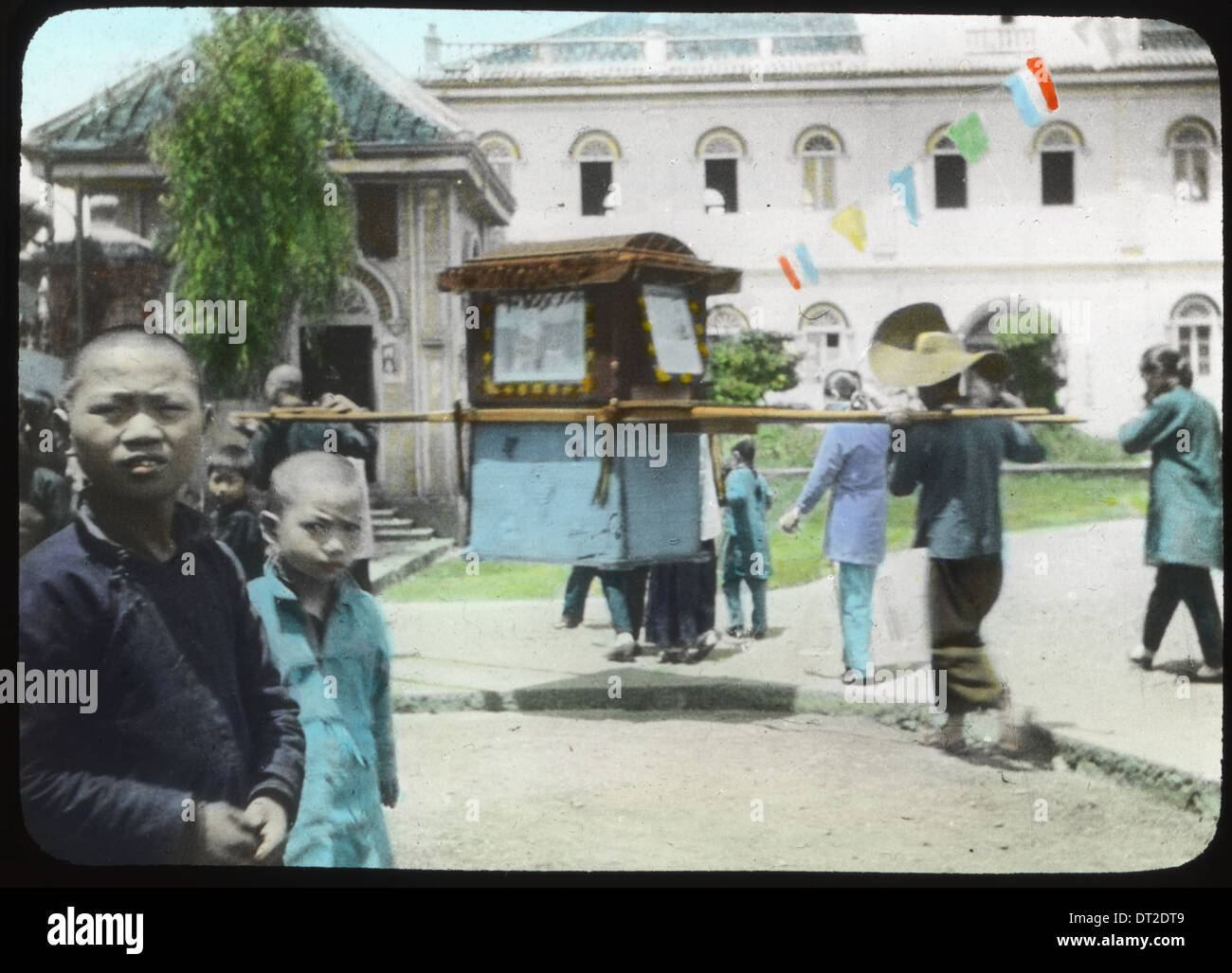 Un gruppo di uomini si vede portare una sedia berlina circondata da passanti in Cina, tra il 1917 e il 1923. Foto Stock