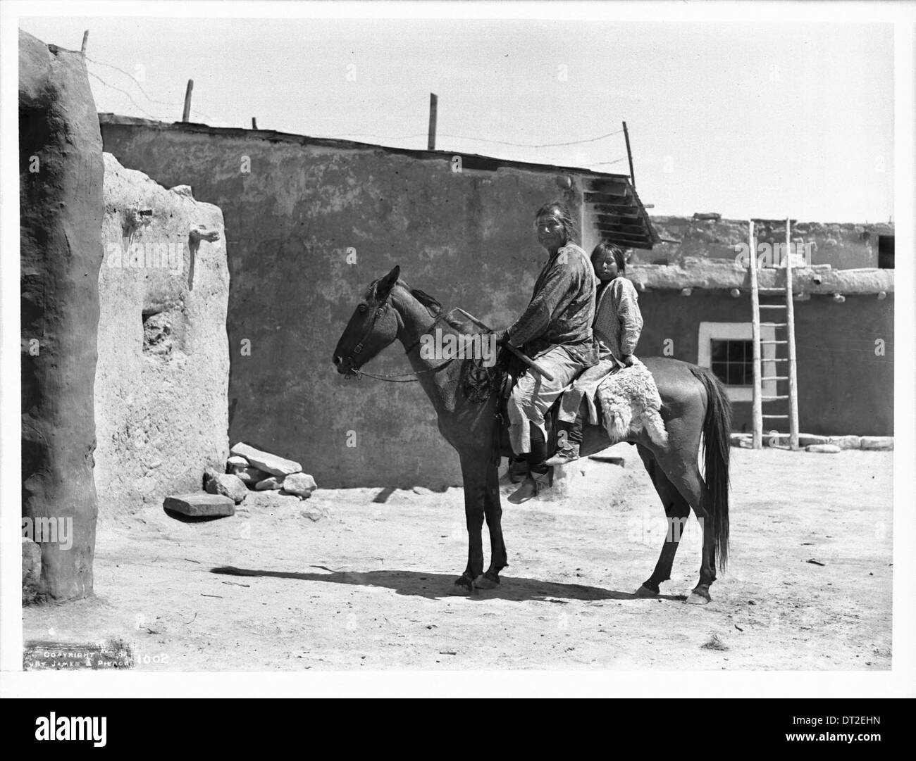Questa fotografia mostra un padre Navajo e sua figlia seduti su un pony mentre visitano un villaggio Hopi intorno al 1901, documentando la vita della famiglia dei nativi americani e le interazioni intertribali. Foto Stock
