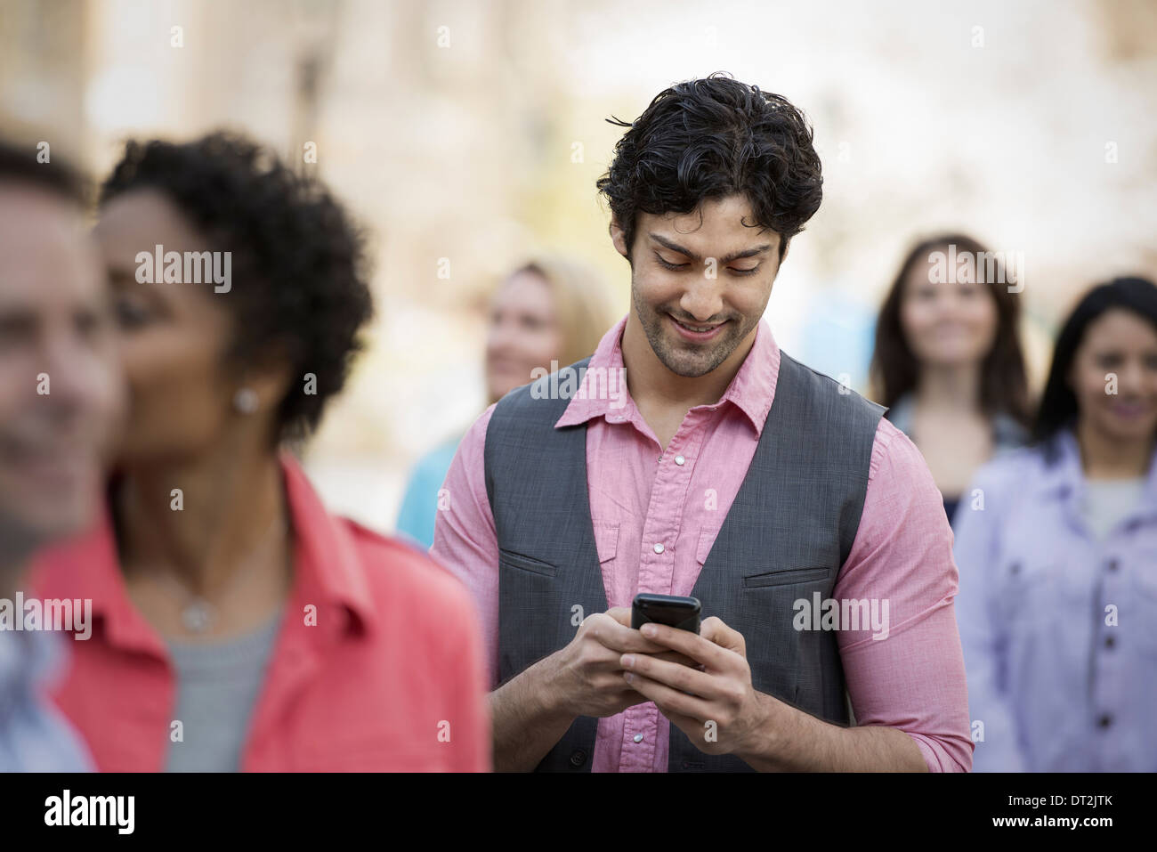 La gente all'aperto nella città in primavera tempo di un uomo che guarda il suo telefono cellulare Foto Stock