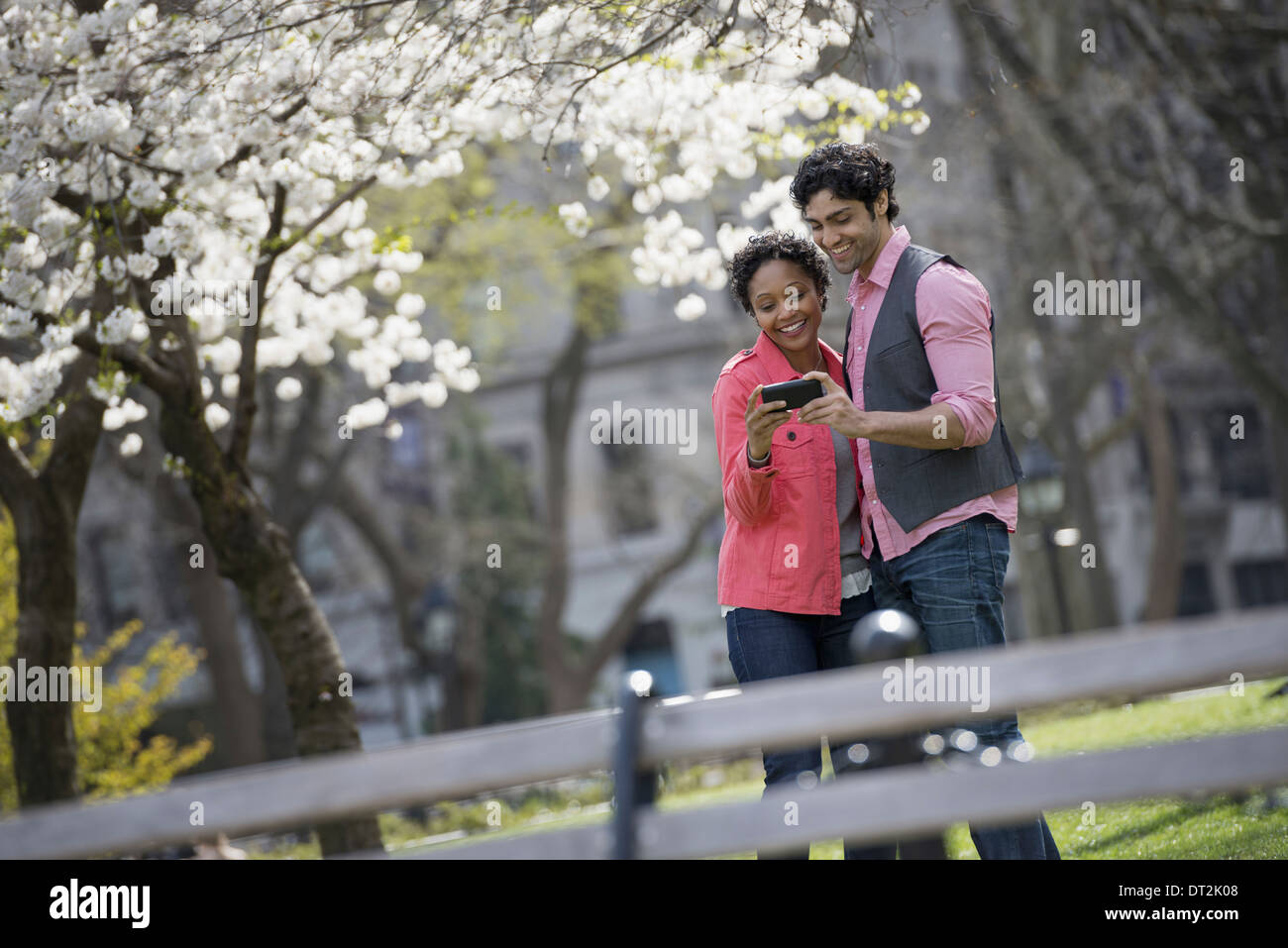 New York City Park di un uomo e di una donna a fianco a fianco di prendere una fotografia con una mano il telefono cellulare Foto Stock