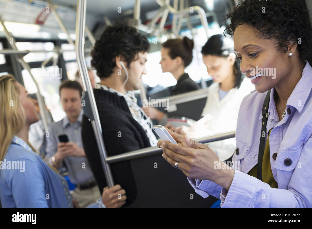 La città di New York uomini e donne city bus trasporto pubblico mantenendo in contatto una giovane donna di controllo o utilizzando il suo telefono cellulare Foto Stock