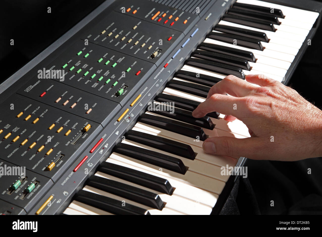 Un sistema elettronico di strumento musicale a tastiera essendo giocato mostra gli esecutori mano destra. Sfondo di colore nero. Foto Stock