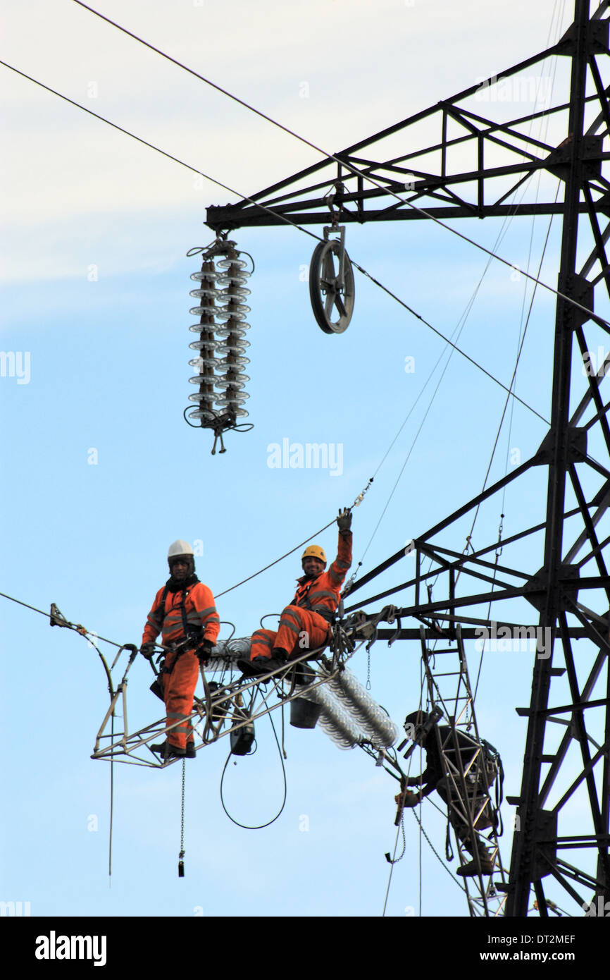 Lavoratori a tralicci di energia elettrica in Italia. I lavori di manutenzione di una linea elettrica ad alta tensione. Foto Stock