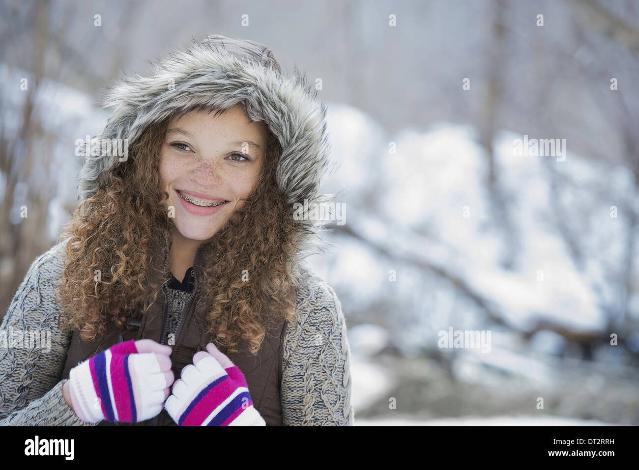 Paesaggio invernale con neve sul terreno di una giovane ragazza in un cappellino con guanti da sci su Foto Stock