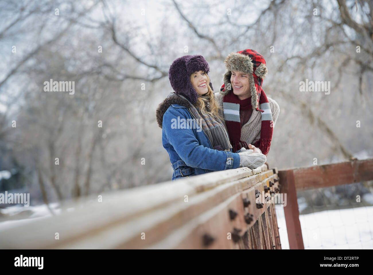 Paesaggio invernale con neve sul terreno una coppia giovane uomo e donna giovane appoggiato su di una recinzione Foto Stock