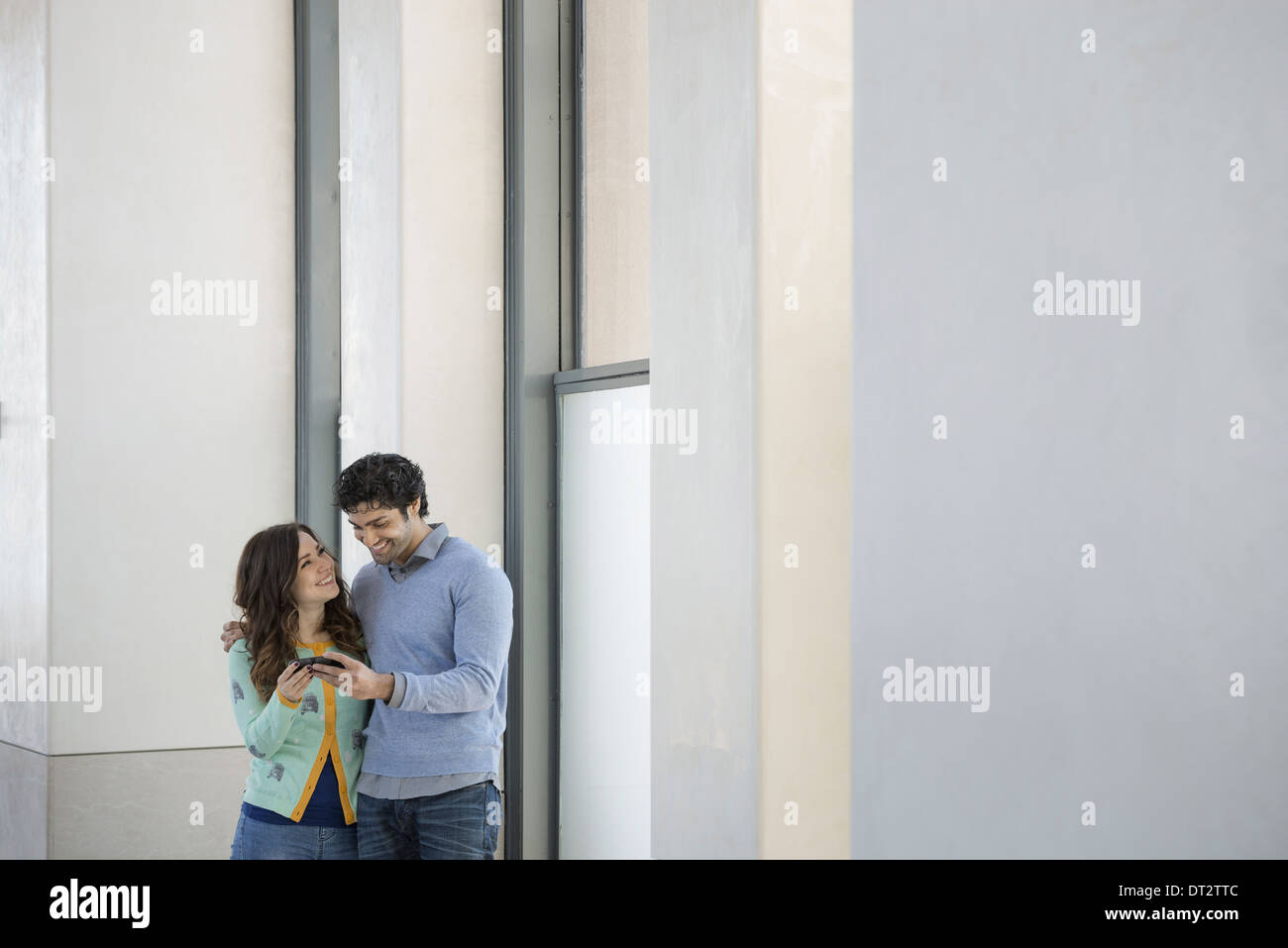 Uno stile di vita urbano una coppia giovane uomo e donna fianco a fianco alla ricerca di un telefono cellulare Foto Stock