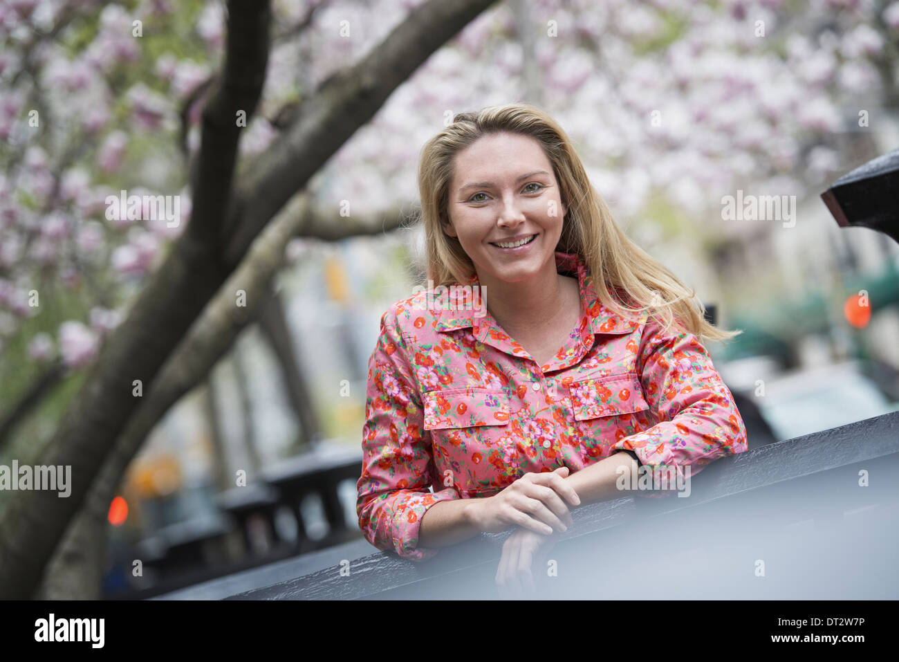 Vista su cityA giovane donna con capelli lunghi biondi all'aperto in un parco della città Foto Stock