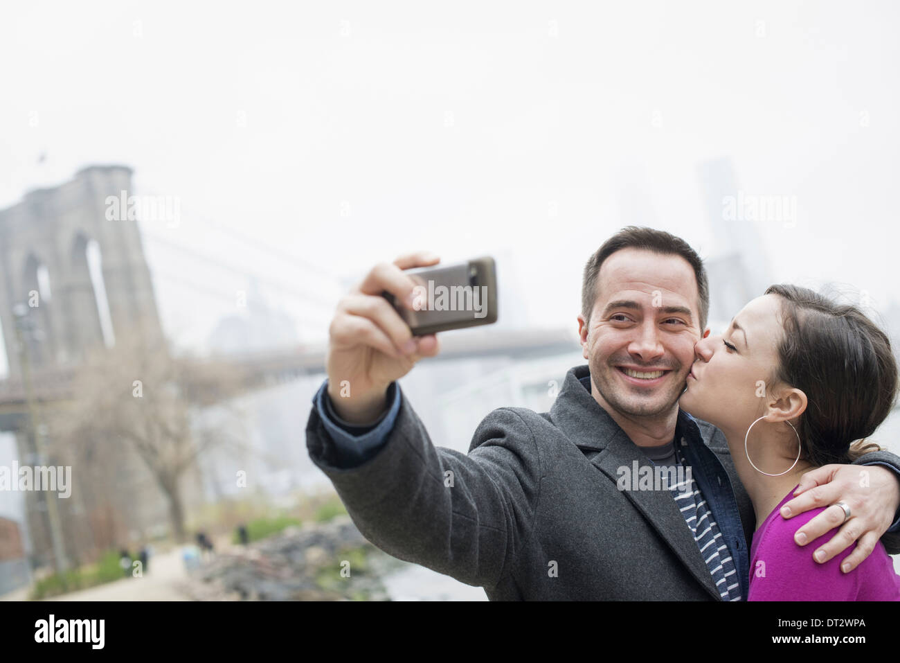 Ponte di Brooklyn attraversando il fiume est un paio di scattare una foto con un telefono un selfy di se stessi Foto Stock