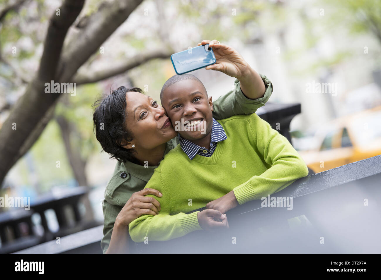 New York City Park nel sole di primavera e la fioritura dei ciliegi una donna di scattare una foto di se stessa e suo figlio con uno smart phone Foto Stock