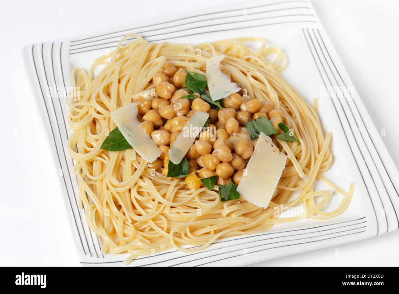 Bavette pasta (come le linguine) con ceci, aglio, peperoncino e salsa di Parmigiano e guarnite con foglie di basilico spezzettate Foto Stock