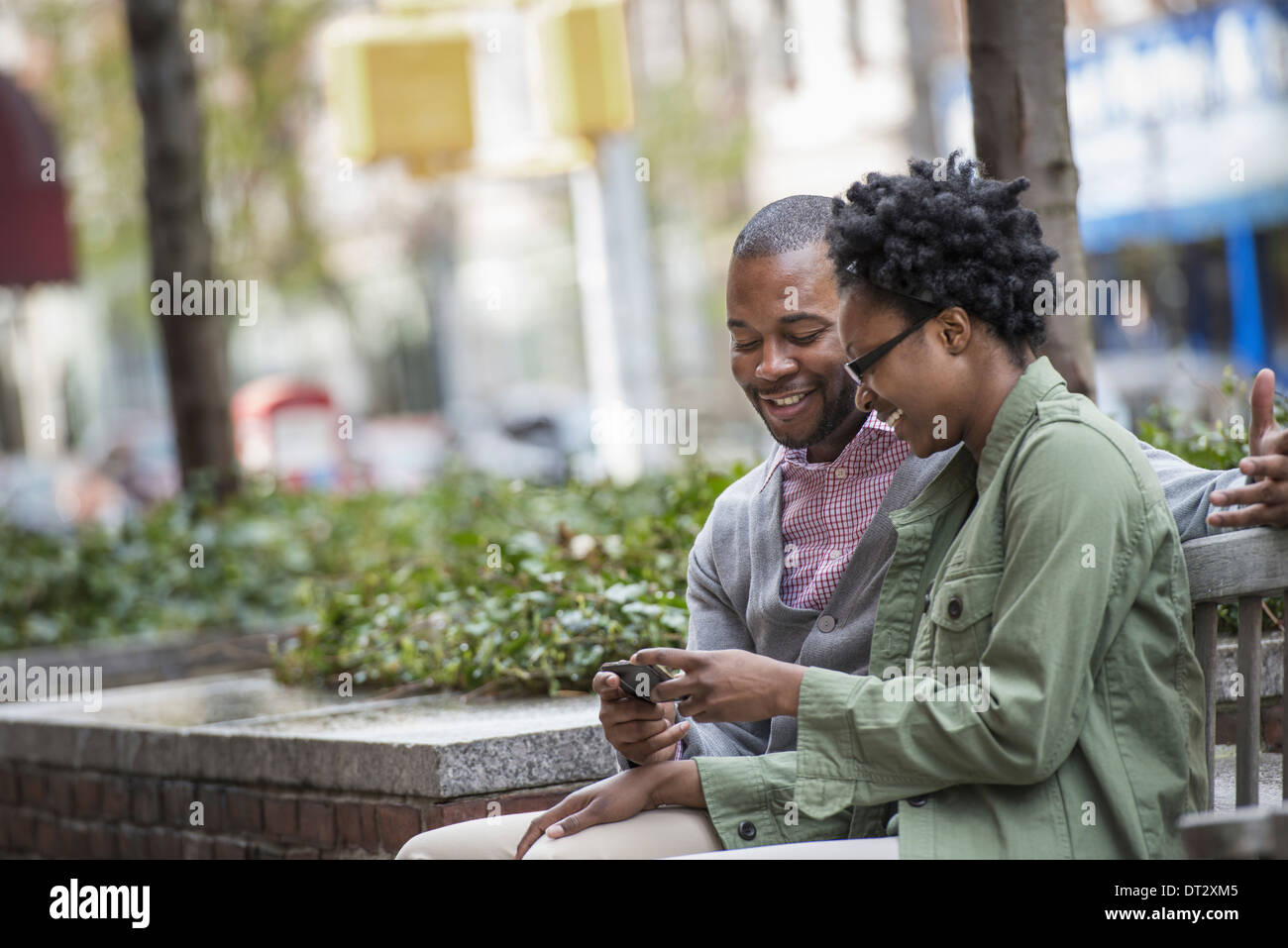 Un giovane seduto a fianco a fianco e guardando una schermata telefono Foto Stock