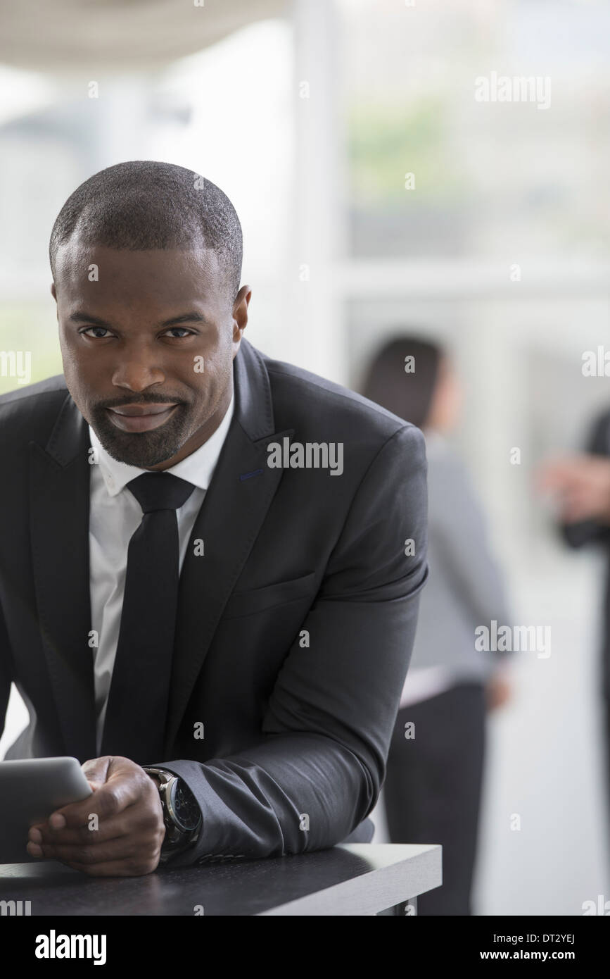 I giovani professionisti al lavoro di un uomo in un business suit utilizzando una tavoletta digitale Foto Stock