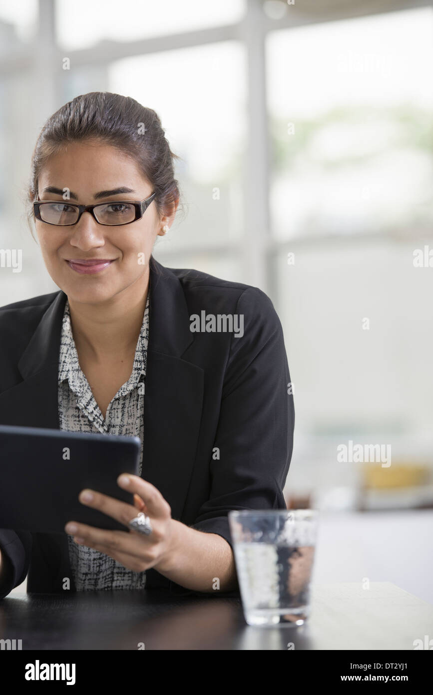 I giovani professionisti al lavoro di una donna che indossa una giacca nera con un nero tavoletta digitale Foto Stock