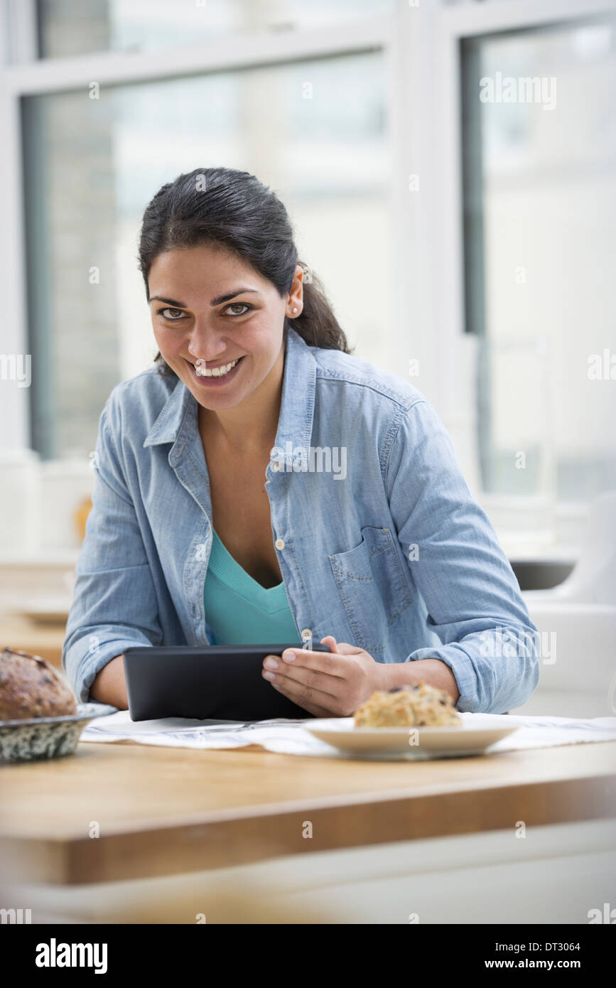 In un ufficio o un interno dell appartamento a New York City una giovane donna in un denim shirt utilizzando una tavoletta digitale Foto Stock